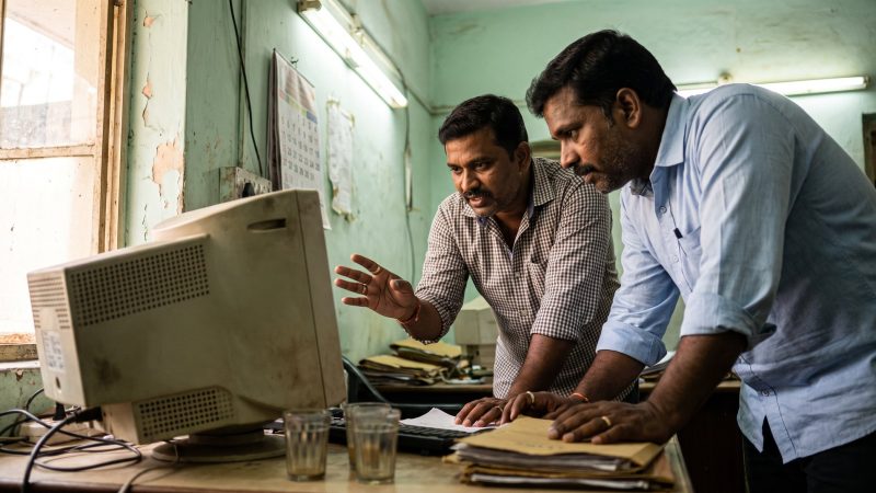 Two bank IT staff examining an ageing desktop terminal in a back office in Chennai