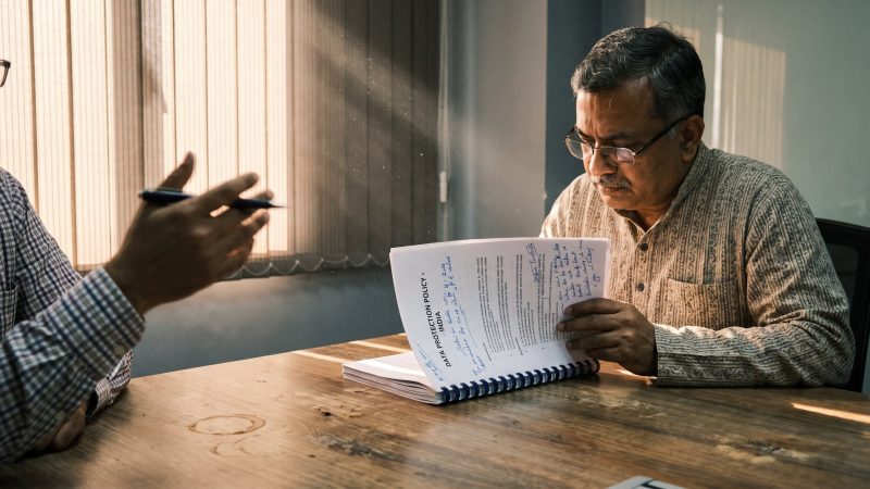 Compliance officer reading an annotated India data protection policy across a meeting table